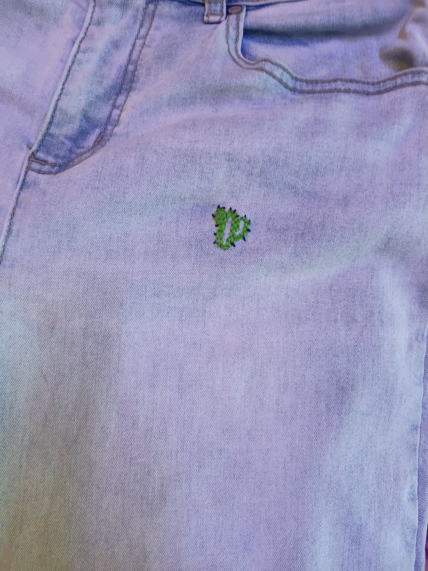 Back view showing embroidered floral stems on pocket of light wash jeans